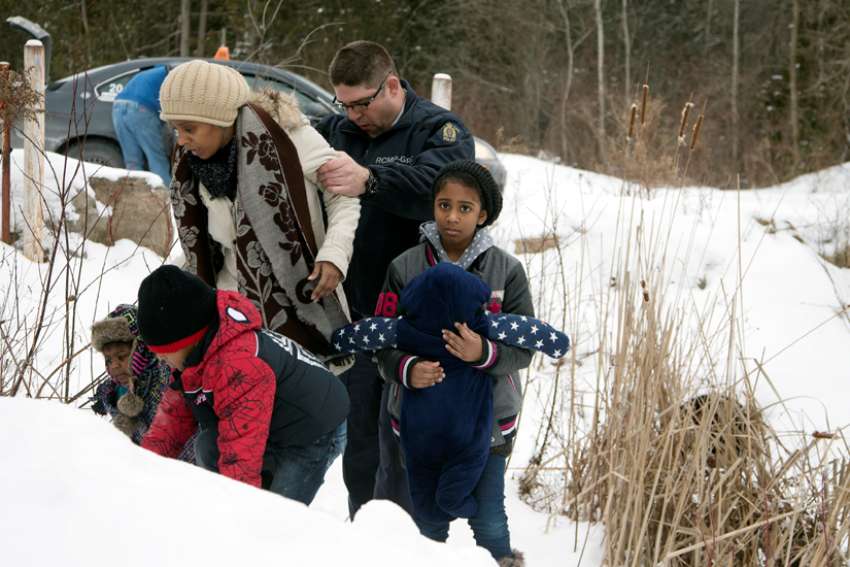 A woman who told police that she and her family were from Sudan is taken into custody by a Royal Canadian Mounted Police officer after arriving Feb.12 by taxi and walking across the U.S.-Canada border into Quebec. CNS photo/Christinne Muschi, Reuters